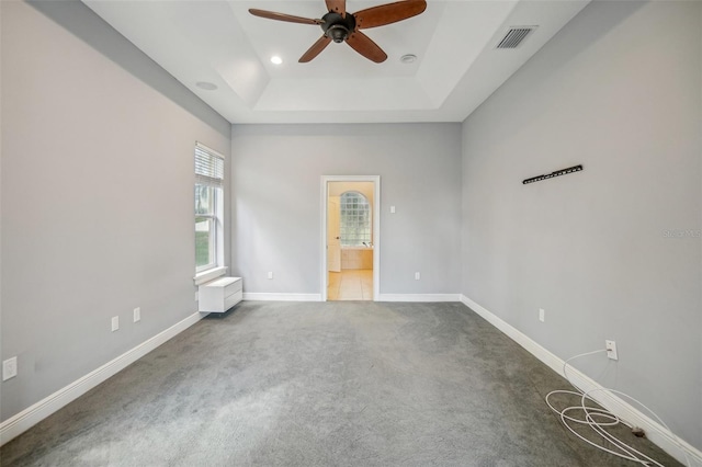 carpeted empty room with visible vents, baseboards, a raised ceiling, a ceiling fan, and recessed lighting