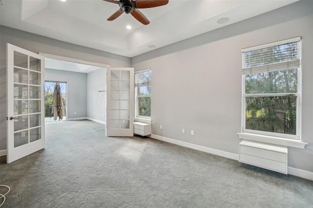 unfurnished room with carpet floors, french doors, a raised ceiling, a ceiling fan, and baseboards