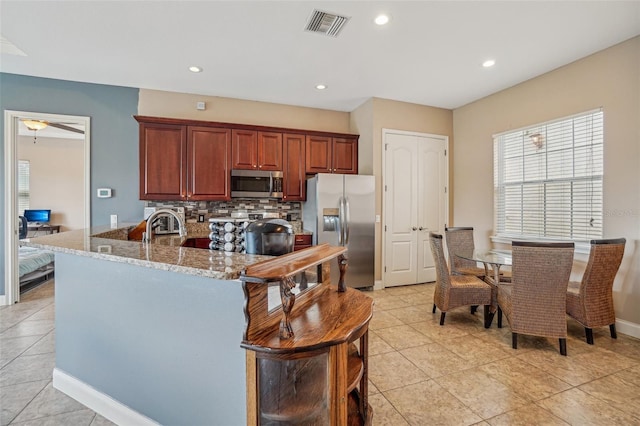 kitchen with light stone counters, visible vents, decorative backsplash, appliances with stainless steel finishes, and a peninsula