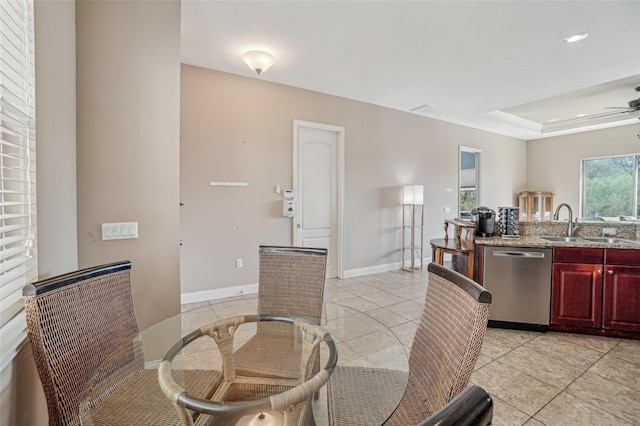 dining space with a ceiling fan, a tray ceiling, baseboards, and light tile patterned floors