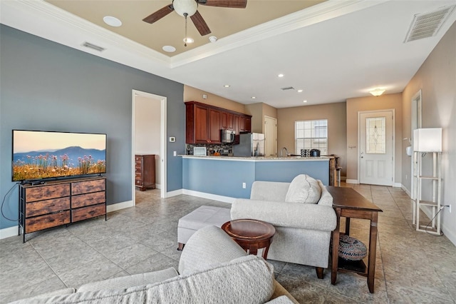 living area with baseboards, visible vents, and a raised ceiling