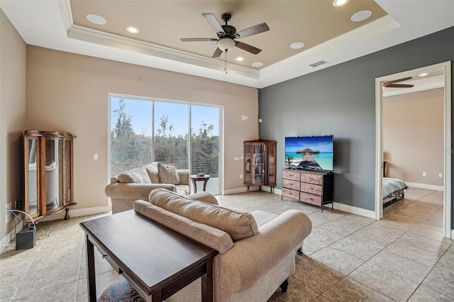 living area with baseboards, ornamental molding, and a raised ceiling