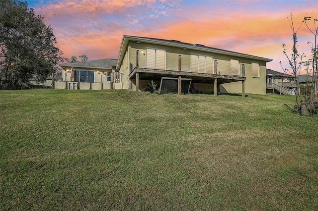 back of house featuring a lawn and a wooden deck