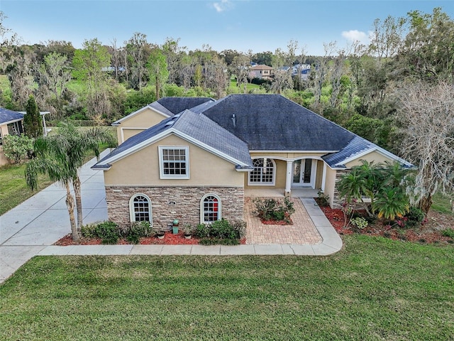 view of front of property with a shingled roof, stone siding, french doors, stucco siding, and a front lawn