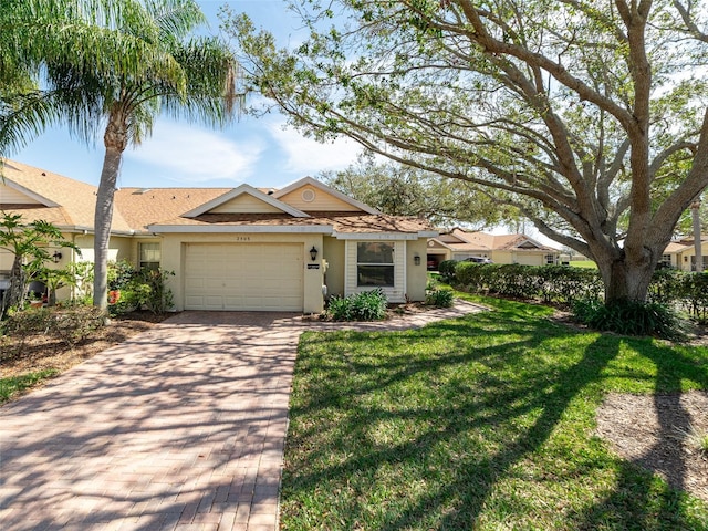 single story home with a front yard, decorative driveway, an attached garage, and stucco siding