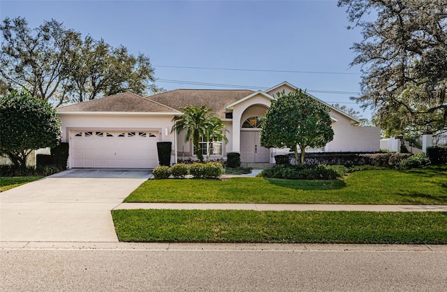 view of front of property featuring driveway, a garage, a front lawn, and stucco siding