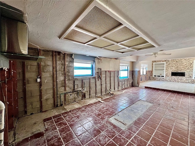 interior space with a fireplace, a ceiling fan, and a textured ceiling