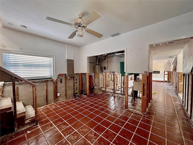 empty room featuring a ceiling fan, plenty of natural light, visible vents, and gas water heater