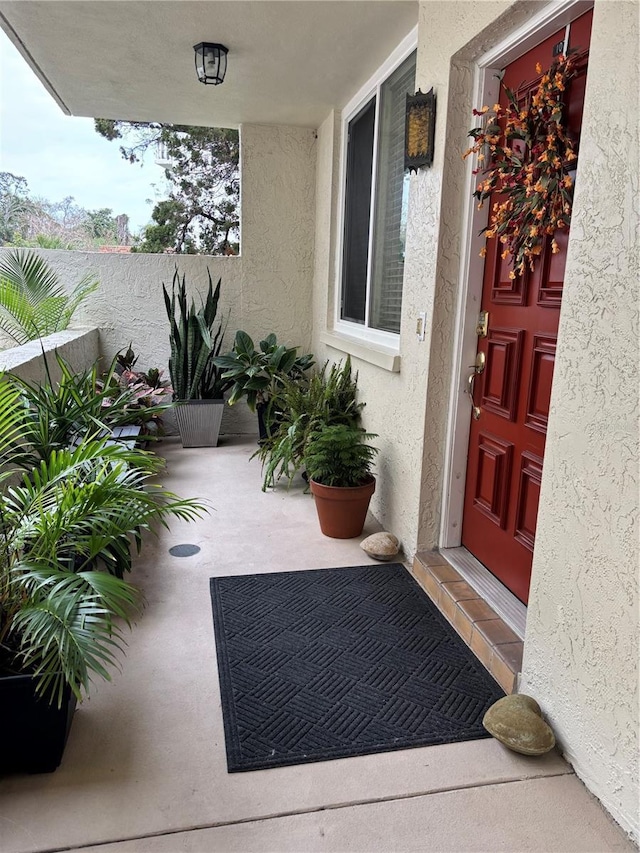 entrance to property with a patio area, fence, and stucco siding