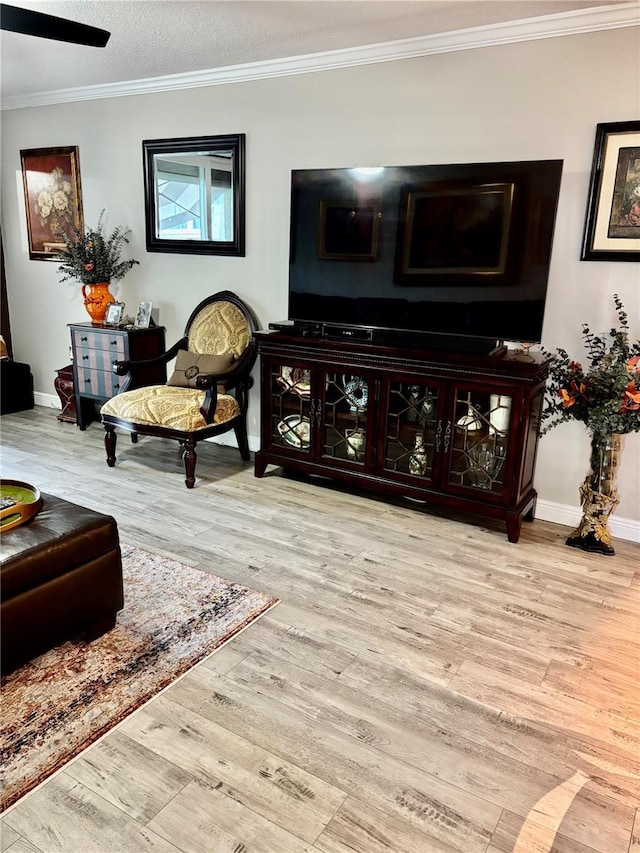 living area featuring crown molding, baseboards, and wood finished floors