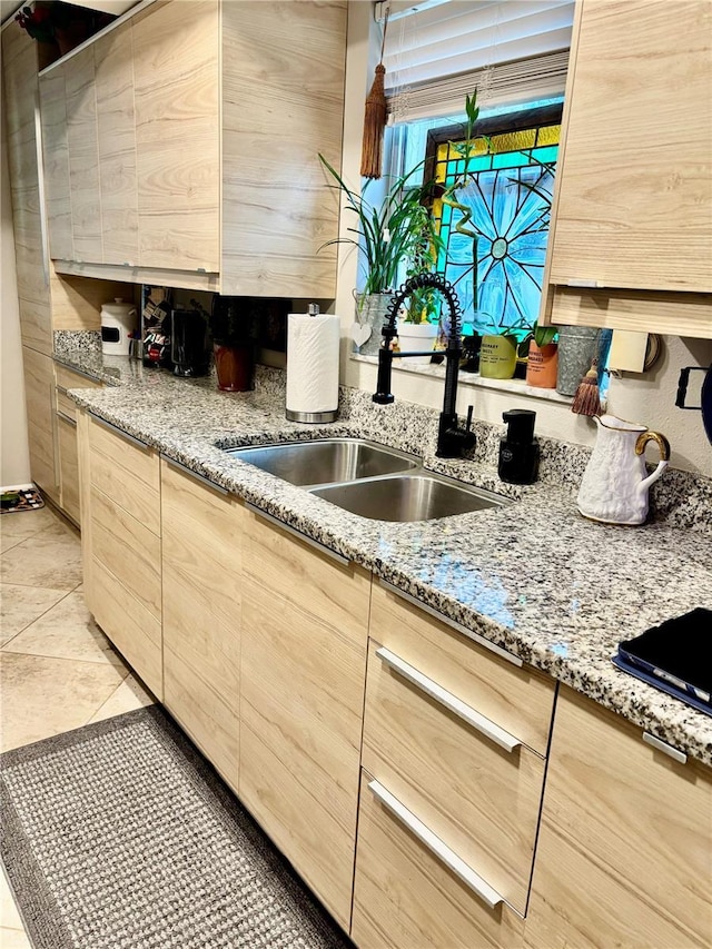 kitchen with light stone counters, light brown cabinets, a sink, and light tile patterned floors