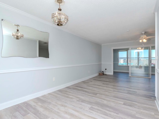 spare room with ornamental molding, ceiling fan with notable chandelier, baseboards, and wood finished floors