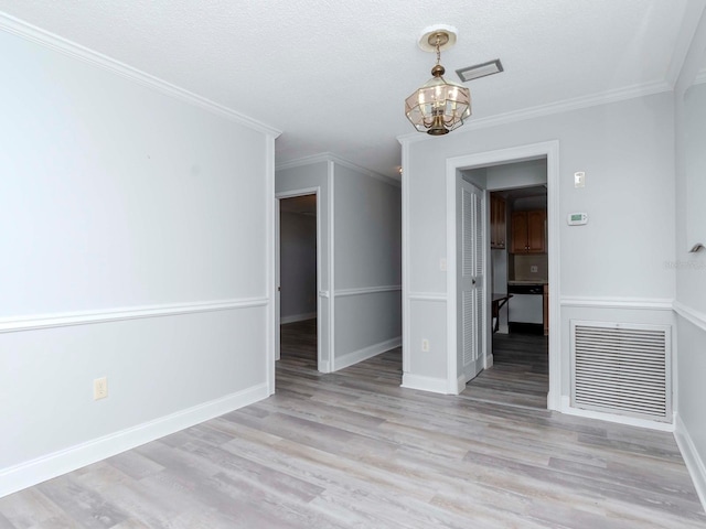 unfurnished dining area featuring visible vents, a chandelier, wood finished floors, and ornamental molding