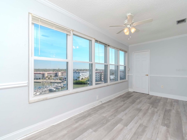 spare room featuring baseboards, visible vents, wood finished floors, crown molding, and a textured ceiling