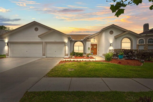 ranch-style home with a front yard, stucco siding, a garage, and concrete driveway