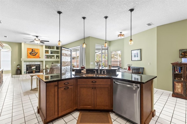 kitchen featuring stainless steel dishwasher, a ceiling fan, visible vents, a sink, and a tile fireplace