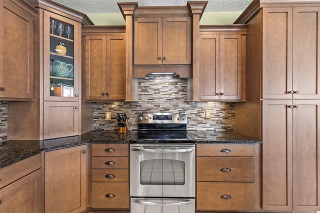 kitchen featuring brown cabinets, glass insert cabinets, decorative backsplash, and stainless steel range with electric cooktop