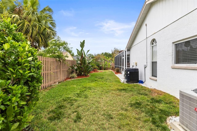 view of yard featuring a fenced backyard, a lanai, and central air condition unit