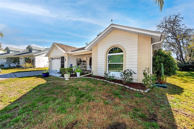 view of front of house with a front yard, concrete driveway, brick siding, and an attached garage