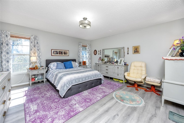 bedroom featuring a textured ceiling, wood finished floors, and baseboards