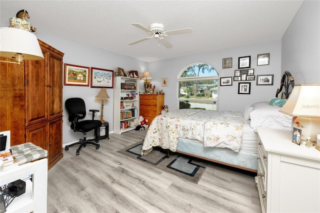 bedroom featuring light wood-style floors, a ceiling fan, and a textured ceiling