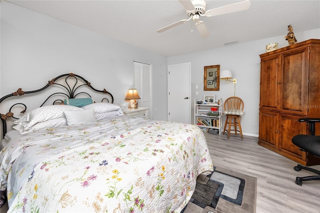 bedroom featuring a textured ceiling, baseboards, light wood-style flooring, and a ceiling fan