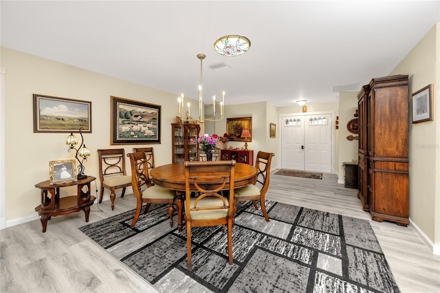 dining space featuring a chandelier, visible vents, light wood-style flooring, and baseboards