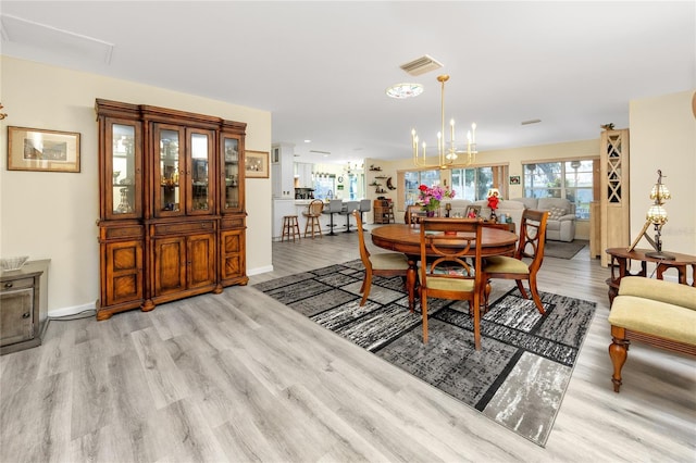 dining room with a chandelier, visible vents, baseboards, and wood finished floors