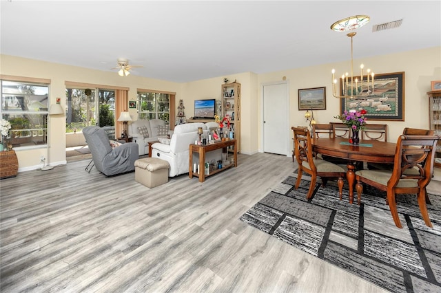 dining room featuring ceiling fan with notable chandelier, wood finished floors, visible vents, and baseboards