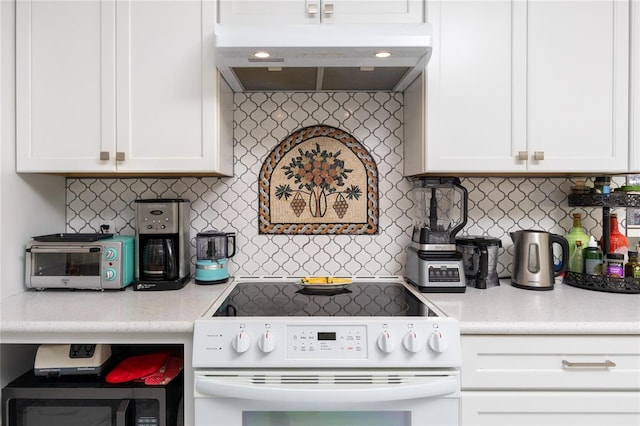 kitchen with tasteful backsplash, electric stove, white cabinets, and under cabinet range hood