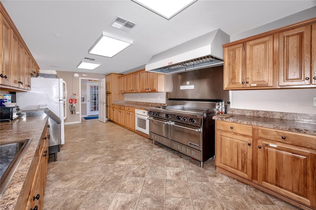 kitchen featuring brown cabinets, visible vents, a sink, white appliances, and premium range hood