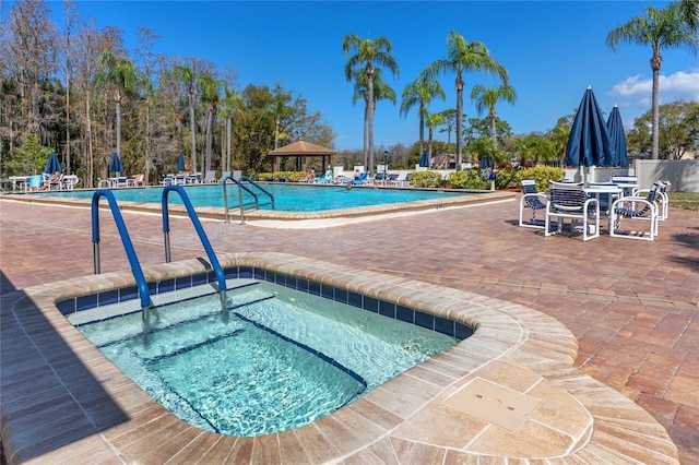 community pool featuring a gazebo, a community hot tub, and a patio