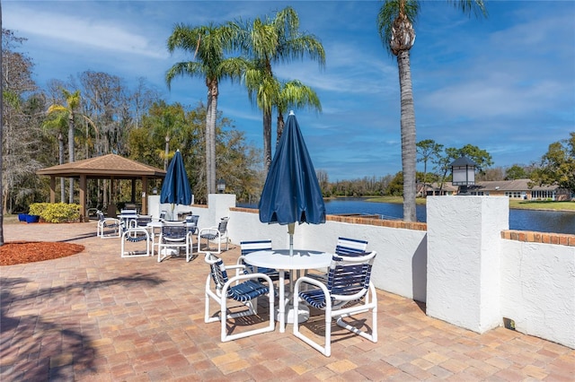 view of patio / terrace featuring outdoor dining area, a water view, and a gazebo