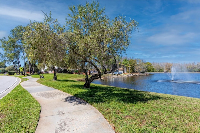 surrounding community with a water view and a lawn