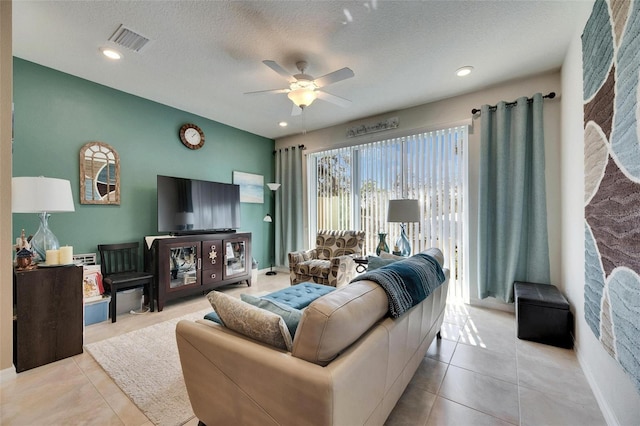 living area featuring a textured ceiling, ceiling fan, visible vents, and tile patterned floors