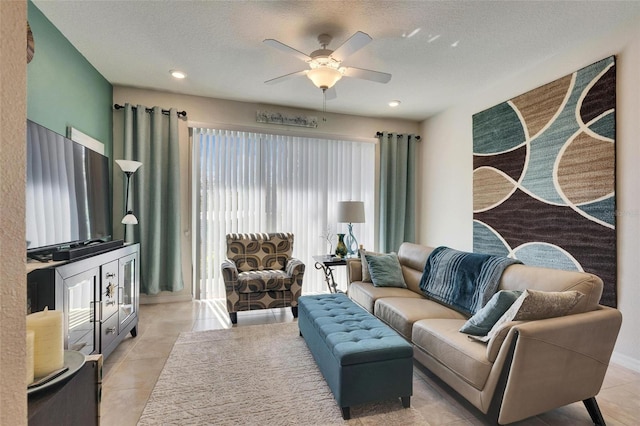 living area featuring light tile patterned floors, a ceiling fan, and a textured ceiling