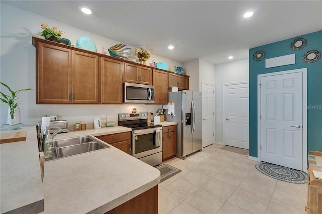 kitchen featuring appliances with stainless steel finishes, brown cabinetry, a sink, and light countertops