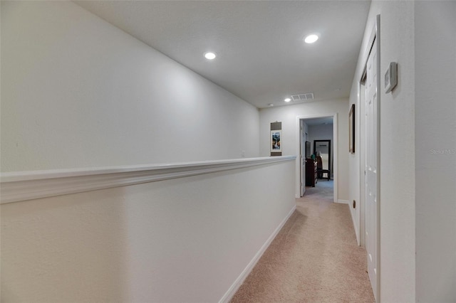 hall featuring baseboards, recessed lighting, visible vents, and light colored carpet