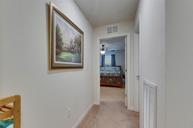 corridor featuring baseboards, visible vents, and light colored carpet