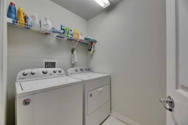 washroom featuring washer and dryer, laundry area, a textured ceiling, and baseboards