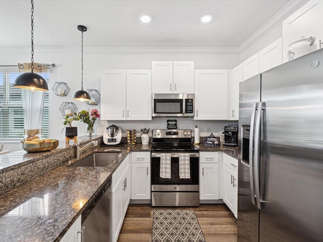 kitchen featuring stainless steel appliances, a sink, white cabinets, dark wood finished floors, and crown molding