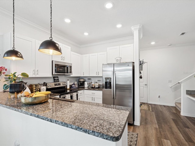 kitchen with appliances with stainless steel finishes, dark stone counters, crown molding, and a peninsula