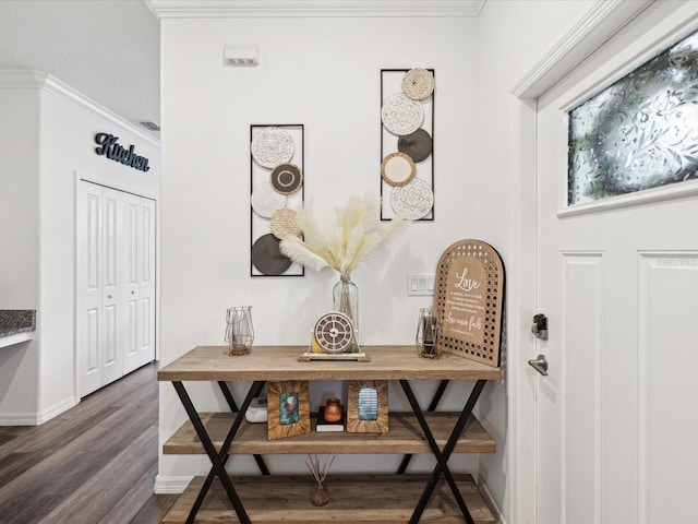 foyer featuring baseboards, wood finished floors, and crown molding