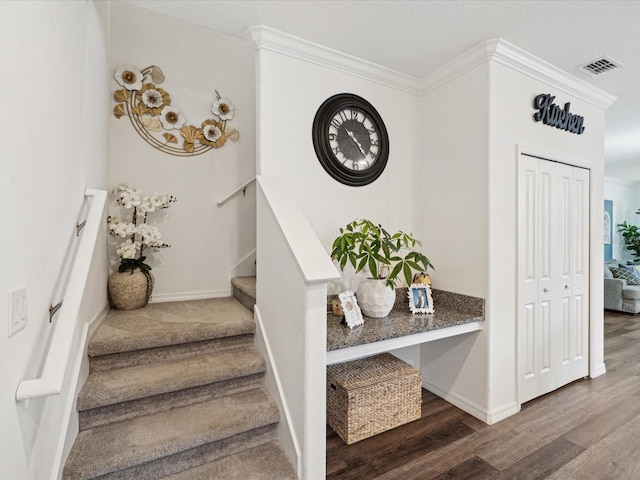 stairs featuring baseboards, crown molding, visible vents, and wood finished floors