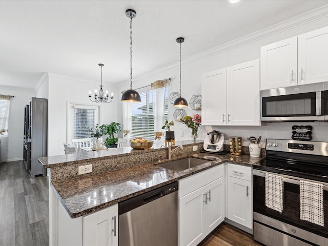 kitchen with crown molding, stainless steel appliances, white cabinets, a sink, and a peninsula