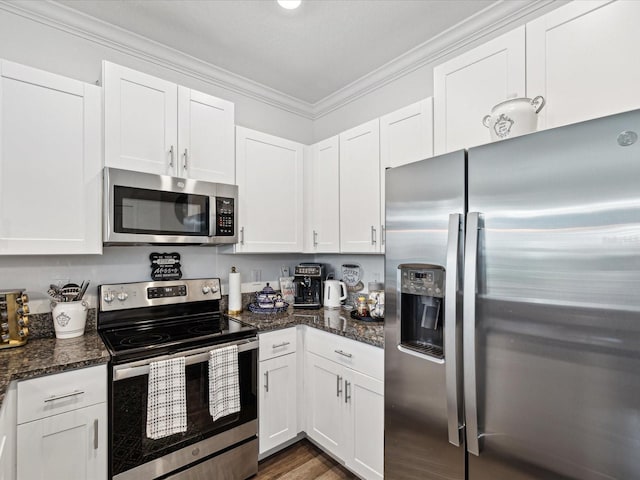 kitchen featuring dark stone counters, dark wood-type flooring, stainless steel appliances, crown molding, and white cabinetry