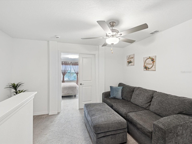 living area with baseboards, visible vents, a ceiling fan, light colored carpet, and a textured ceiling