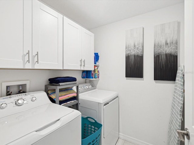 laundry area featuring washer and clothes dryer, cabinet space, and baseboards