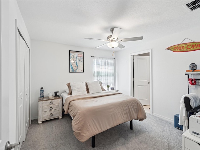 bedroom featuring a textured ceiling, carpet floors, visible vents, baseboards, and a ceiling fan