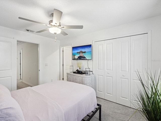 bedroom featuring light carpet, a closet, visible vents, and a ceiling fan